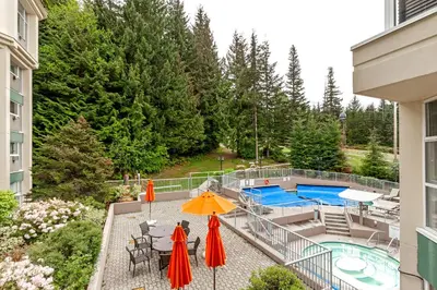 a balcony with an umbrella and a swimming pool at The Woodrun Lodge by Whiski Jack in Whistler