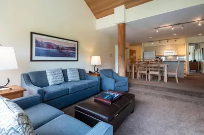 a living room with blue couches and a dining room at The Ironwood on Blueberry Hill in Whistler