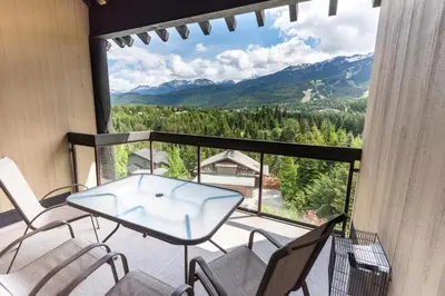 a balcony with a table and chairs and mountains at The Ironwood on Blueberry Hill in Whistler