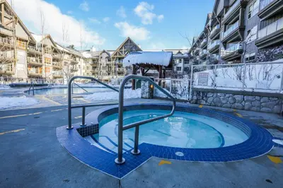 a hot tub in a courtyard with snow on it at The Aspens by Whiski Jack in Whistler