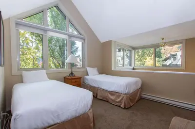 two beds in a room with two windows at Village Gate House by Whiski Jack in Whistler