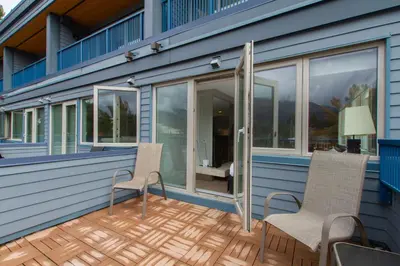 a deck with two chairs and windows on a house at Village Gate House by Whiski Jack in Whistler