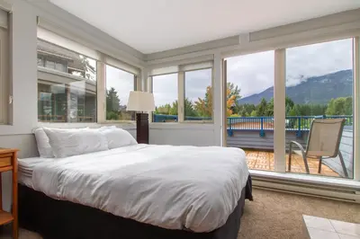 a bedroom with a bed and a large window at Village Gate House by Whiski Jack in Whistler