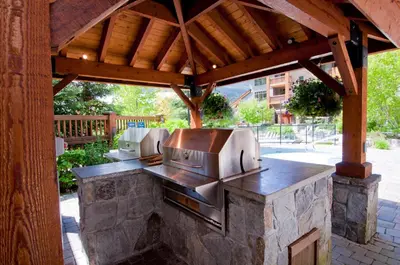 a patio with an outdoor kitchen with a grill at First Tracks Lodge, by Lodging Ovations in Whistler
