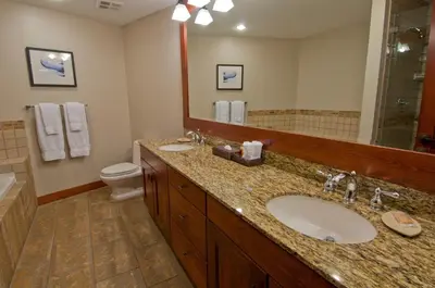 a bathroom with a sink and a toilet and a mirror at First Tracks Lodge, by Lodging Ovations in Whistler