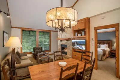a dining room and living room with a chandelier at First Tracks Lodge, by Lodging Ovations in Whistler
