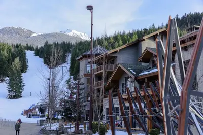 a man standing in front of a ski lodge at First Tracks Lodge, by Lodging Ovations in Whistler