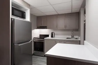 a kitchen with stainless steel appliances and wooden cabinets at Travelodge by Wyndham Grande Prairie in Grande Prairie