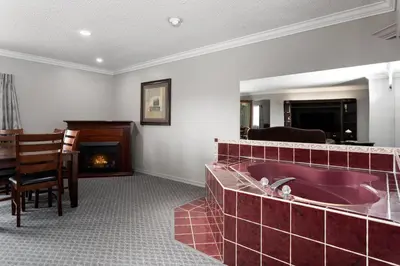 a bathroom with a red tub and a fireplace at Travelodge by Wyndham Grande Prairie in Grande Prairie