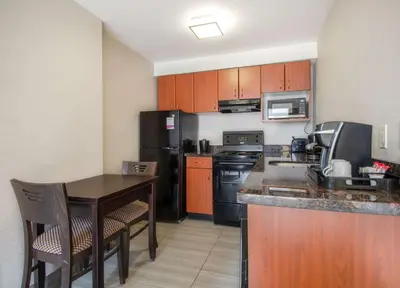 a kitchen with wooden cabinets and a table with chairs at Coast Calgary Downtown Hotel & Suites by APA in Calgary