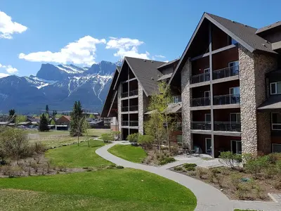 a building with a walkway and mountains in the background at Paradise Resort Club and Spa in Canmore