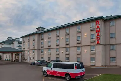a van parked in a parking lot in front of a hotel at Ramada by Wyndham Red Deer Hotel & Suites in Red Deer