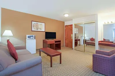 a living room with a couch and a desk with a television at Ramada by Wyndham Red Deer Hotel & Suites in Red Deer