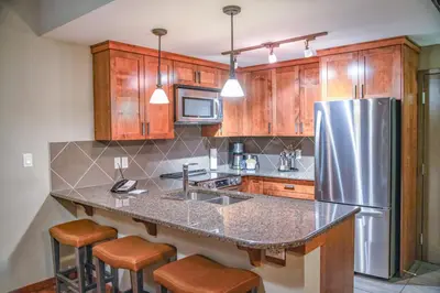 a kitchen with a stainless steel refrigerator and wooden cabinets at Stoneridge Mountain Resort in Canmore