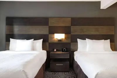 a hotel room with two beds and a nightstand between them at Days Inn by Wyndham Calgary South in Calgary