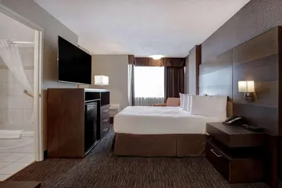 a hotel room with a bed and a television and a tub at Days Inn by Wyndham Calgary South in Calgary