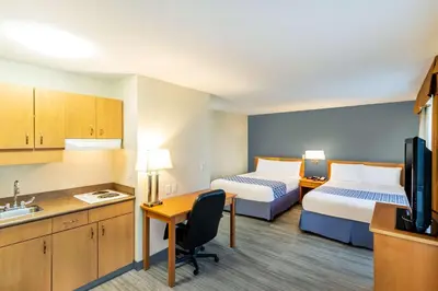 a hotel room with two beds and a desk and a kitchen at Econo Lodge Inn & Suites University in Calgary
