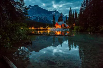 a cabin on a lake at night with its lights on at Emerald Lake Lodge in Field