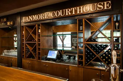 a bar with a counter with wine bottles at The Georgetown Inn in Canmore