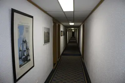 a corridor of a hallway with a long aisle with a picture at Hillcrest Motel in Swan Hills