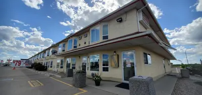 a building with blue windows in a parking lot at Western Budget Motel Cold Lake in Cold Lake
