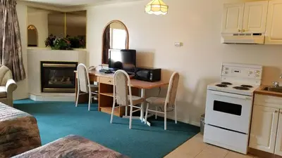 a kitchen with a table with chairs and a television at Western Budget Motel Cold Lake in Cold Lake