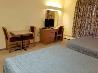 a hotel room with a bed and a desk with a television at New Imperial Inn in Cold Lake
