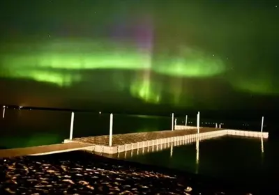 a pier with the green northern lights in the sky at New Imperial Inn in Cold Lake