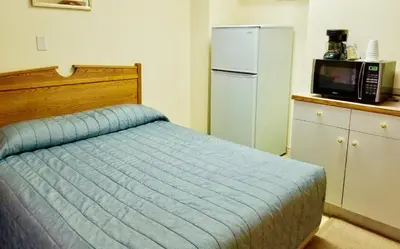 a bedroom with a bed and a refrigerator and a microwave at New Imperial Inn in Cold Lake