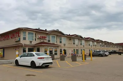 a white car parked in a parking lot in front of a hotel at Western Budget Motel #3 Whitecourt in Whitecourt