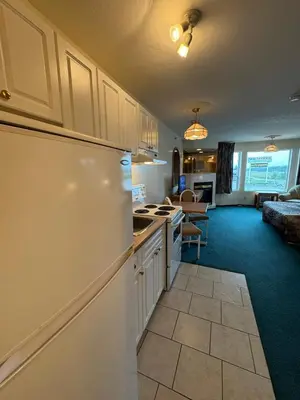 a kitchen with a white refrigerator and a living room at Western Budget Motel #3 Whitecourt in Whitecourt