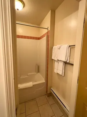 a bathroom with a tub and a shower with towels at Western Budget Motel #3 Whitecourt in Whitecourt