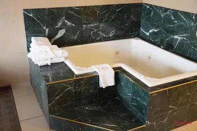 a bathtub in a hotel room with black marble at Ramada by Wyndham Kelowna Hotel & Conference Center in Kelowna
