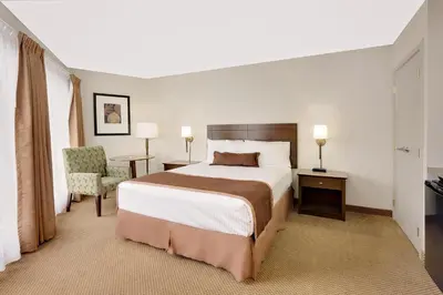 a hotel room with a bed and a chair at Ramada by Wyndham Kamloops in Kamloops