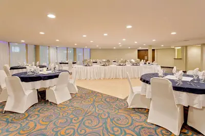 a banquet hall with white tables and white chairs at Ramada by Wyndham Kamloops in Kamloops