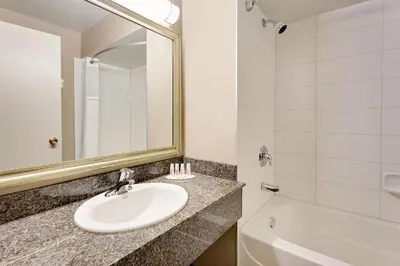 a bathroom with a sink and a mirror and a tub at Ramada by Wyndham Kamloops in Kamloops