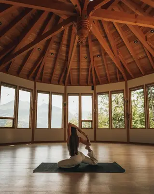 a woman doing a yoga pose in a room with windows at The Sentinel in Kaslo