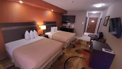 a hotel room with two beds and a desk at Wabasca Inn in Wabasca