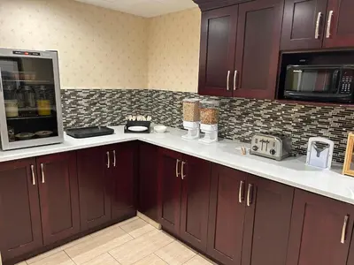 a kitchen with dark wood cabinets and a microwave at Prestige Aberdeen Lodge Kamloops in Kamloops