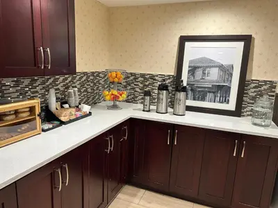 a kitchen with brown cabinets and a picture of a house at Prestige Aberdeen Lodge Kamloops in Kamloops