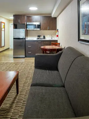 a living room with a couch and a kitchen at Prestige Aberdeen Lodge Kamloops in Kamloops