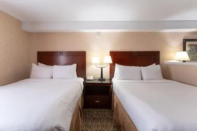 two beds in a hotel room with two lamps at Prestige Aberdeen Lodge Kamloops in Kamloops
