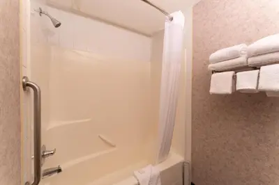 a bathroom with a tub and a shower with towels at Prestige Aberdeen Lodge Kamloops in Kamloops