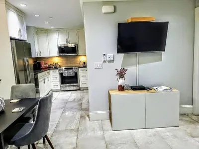 a kitchen with white cabinets and a tv on the wall at New Urban Modern Main Street House in Vancouver