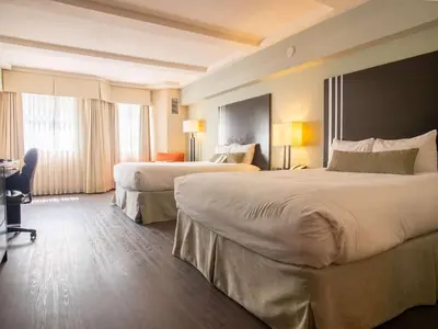 a hotel room with two beds and a desk at Coast Kamloops Hotel & Conference Centre in Kamloops