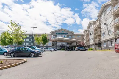 a parking lot with cars parked in front of a hotel at Sandman Hotel and Suites Abbotsford in Abbotsford