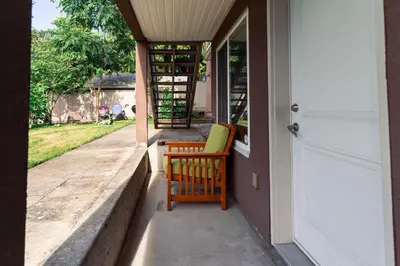 a porch with a wooden chair on a house at Vancouver Yuelai Guesthouse in Coquitlam