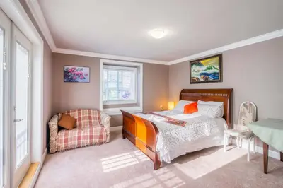 a bedroom with a bed and a chair and a table at Vancouver Yuelai Guesthouse in Coquitlam