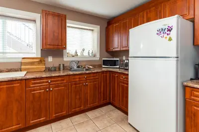 a kitchen with wooden cabinets and a white refrigerator at Vancouver Yuelai Guesthouse in Coquitlam