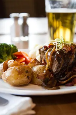 a plate of food with meat and vegetables on a table at The Lodge at Arrow Lakes in Nakusp
